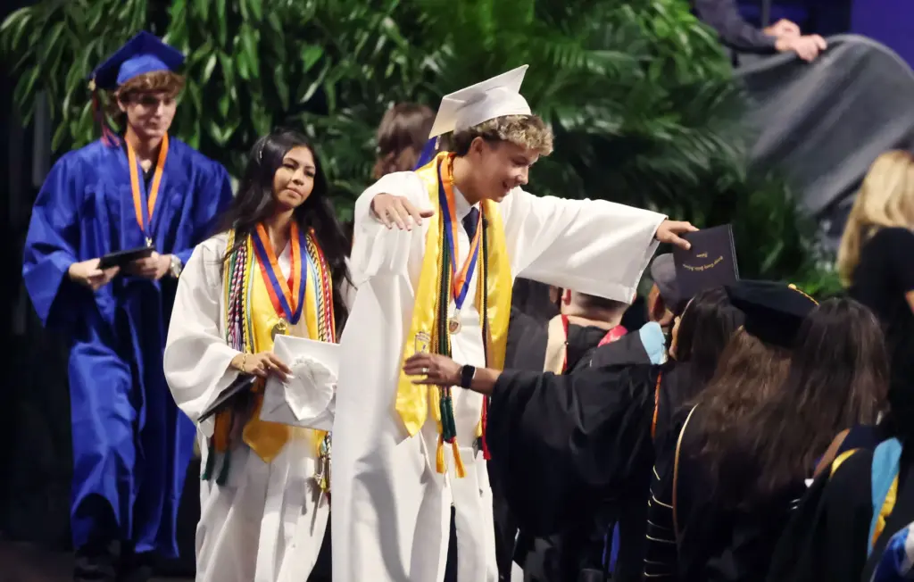 A graduate celebrates after receiving his diploma during West Orange...