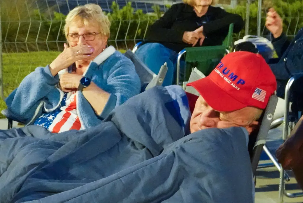 A supporter of President Donald Trump takes a nap while...