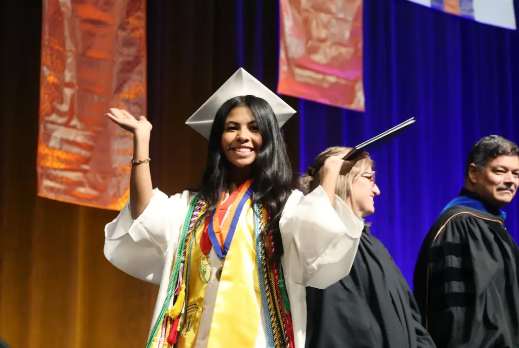 A graduate celebrates after receiving her diploma during West Orange...