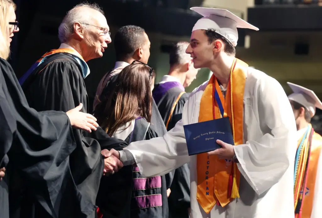 Valedictorian Lucca Carvalho Magalhaes shakes hands after receiving his diploma...