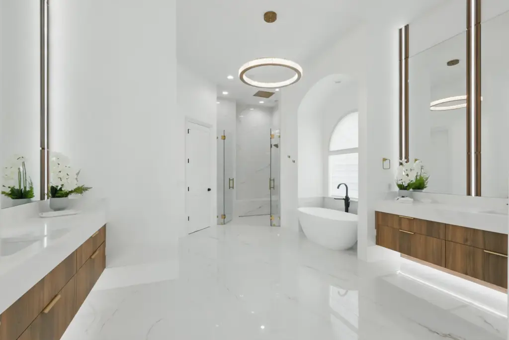 The gleaming white, spa-inspired primary bathroom offers his-and-hers floating vanities,...