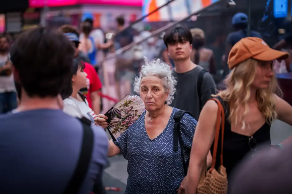 A person uses a fan as they wait in line to purchase Broadway tickets.