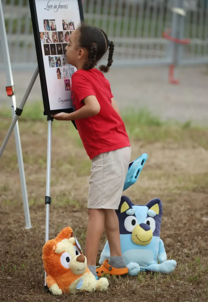 A child looks at photographs displayed during a community vigil...