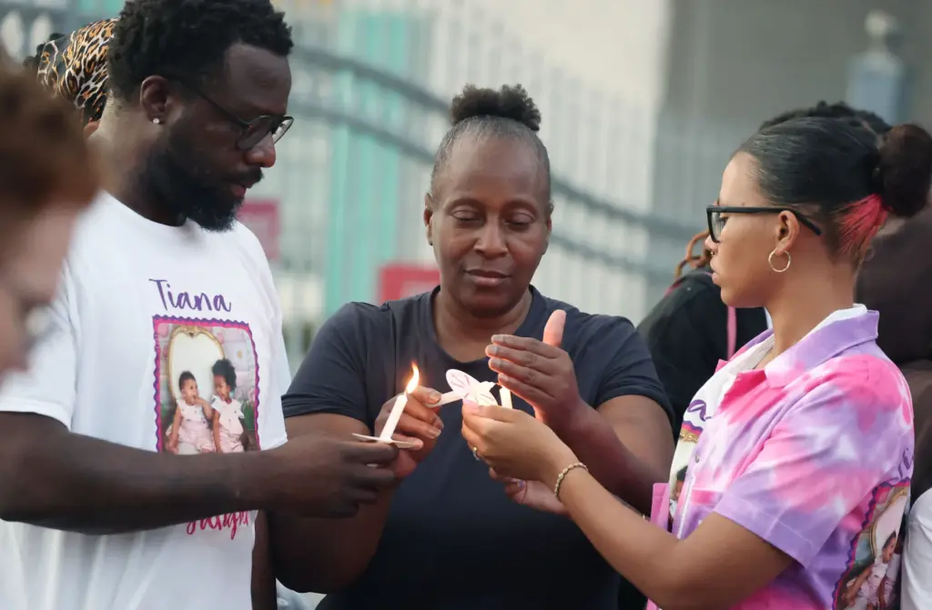 Mourners light candles during a community vigil for 2-year-old Tiana...