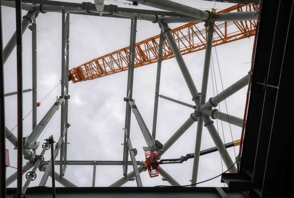 Workers on a lift tighten bolts during a construction tour...
