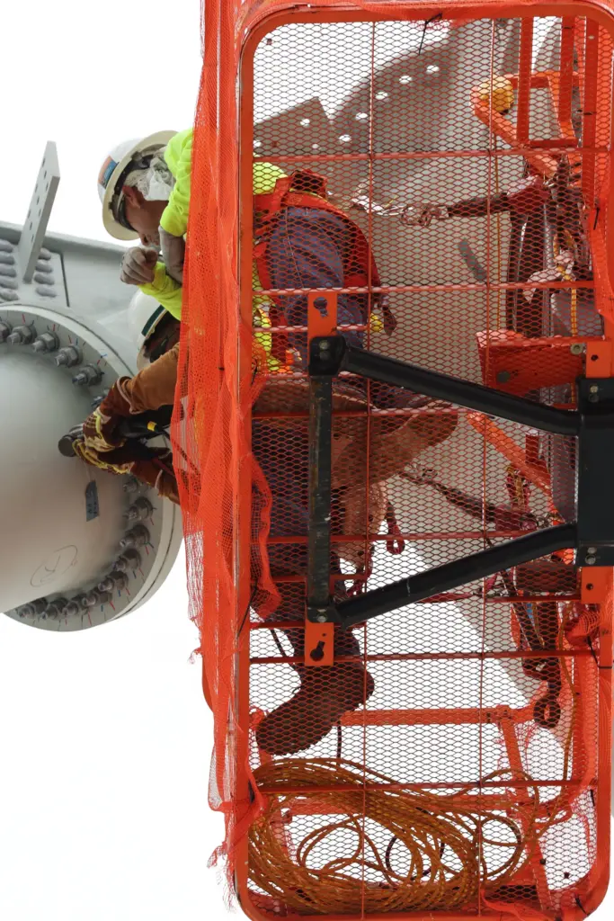 Workers on a lift tighten bolts during a construction tour...