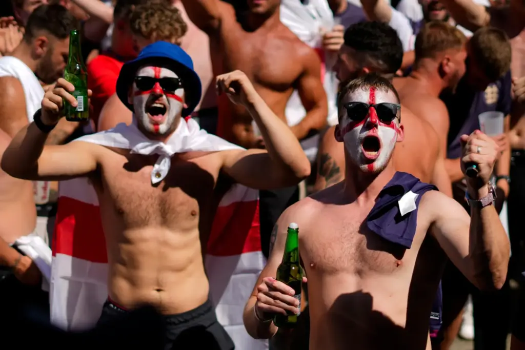 Men with face painted in the colors on the England flag chant slogans and drink beers.