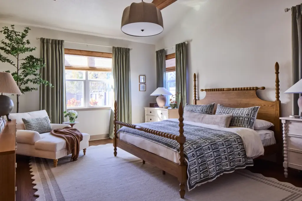 A spindle bed in warm wood anchors the main bedroom,...