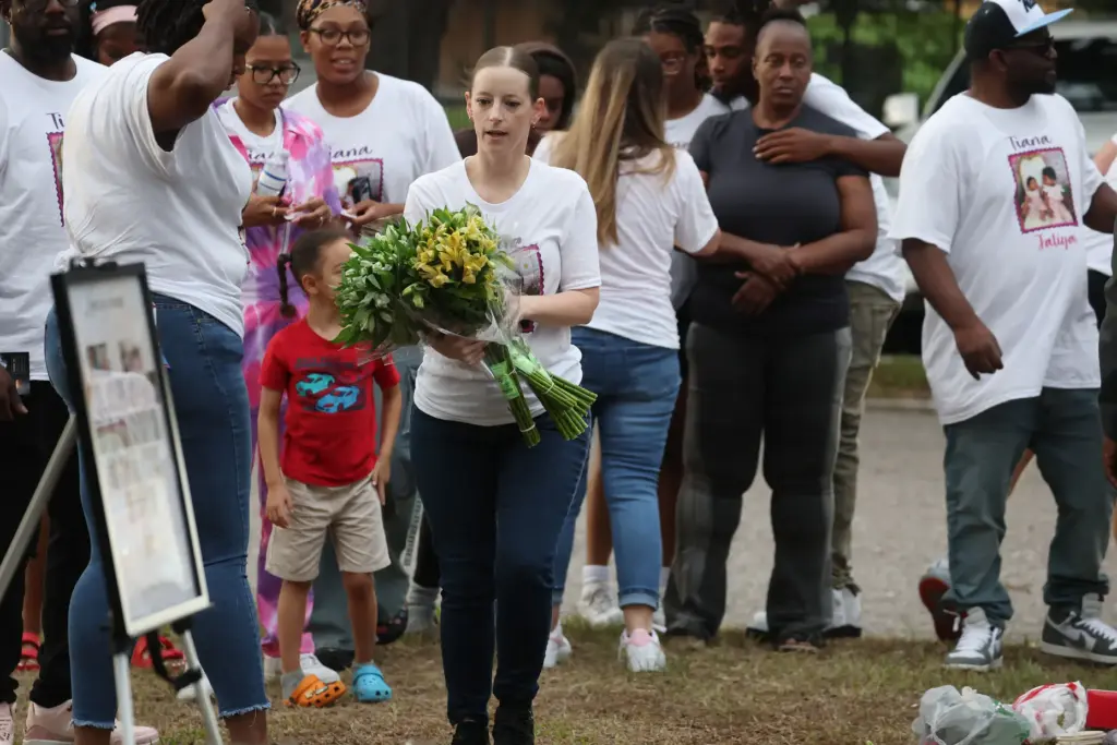 A mourner carries flowers during a community vigil for 2-year-old...
