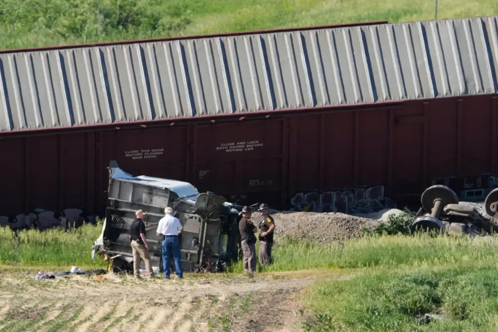 Workers and law enforcement examine debris from a semi-truck after...