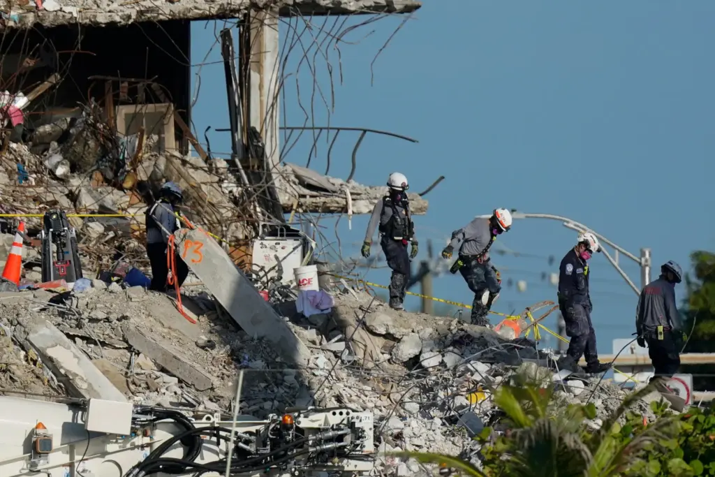 Search and rescue workers descend from the rubble pile at the Champlain Towers South building.