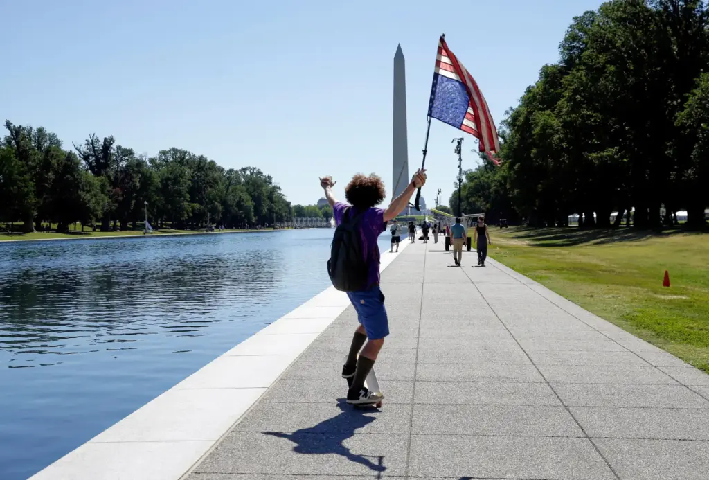 A man with an upside-down U.S. flag is seen near...