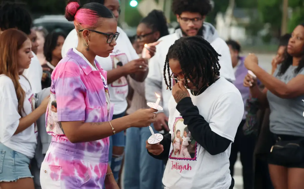 Mourners light candles during a community vigil for 2-year-old Tiana...