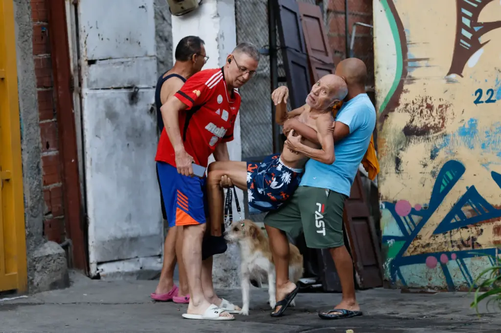 Neighbors helps a man evacuate his damaged home after an...