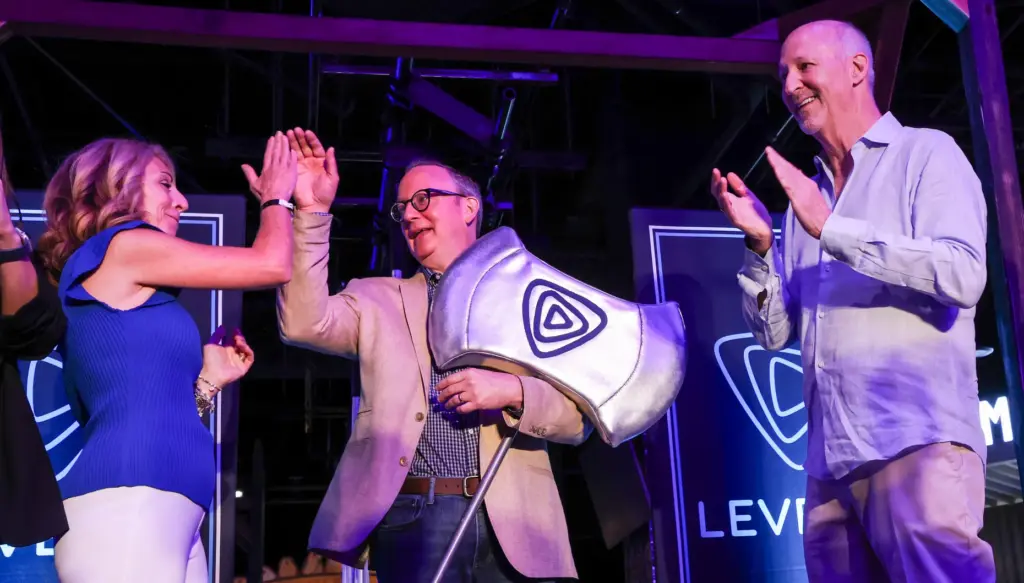 Level99 CEO Matt DuPlessie, center, high-fives Disneyâs Debbie Hart as...