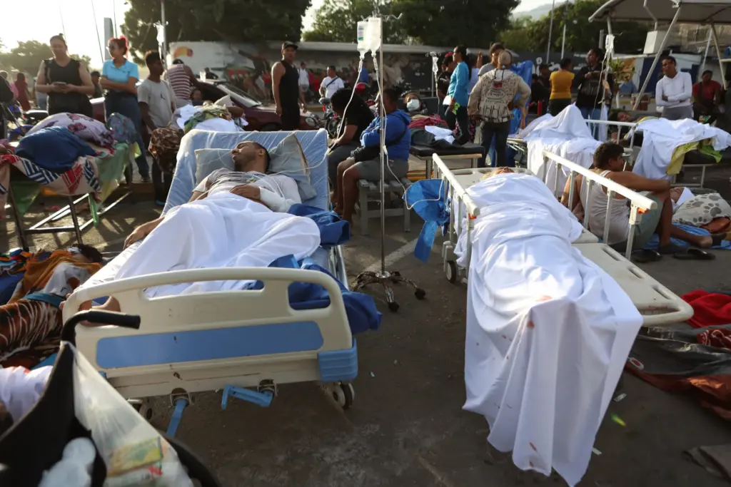 Patients lie outside a hospital evacuated after it was damaged in an earthquake.