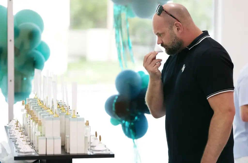 Mike Allen smells a fragrance sample during a grand opening...