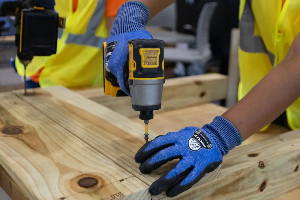 A camper wears protective gloves while drilling for a construction...