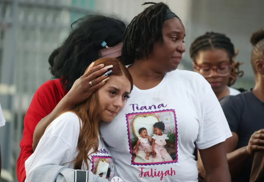 Mourners grieve during a community vigil for 2-year-old Tiana Rae...