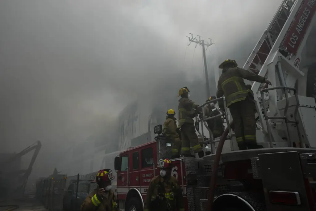 Firefighters work from a ladder truck while fighting a warehouse...