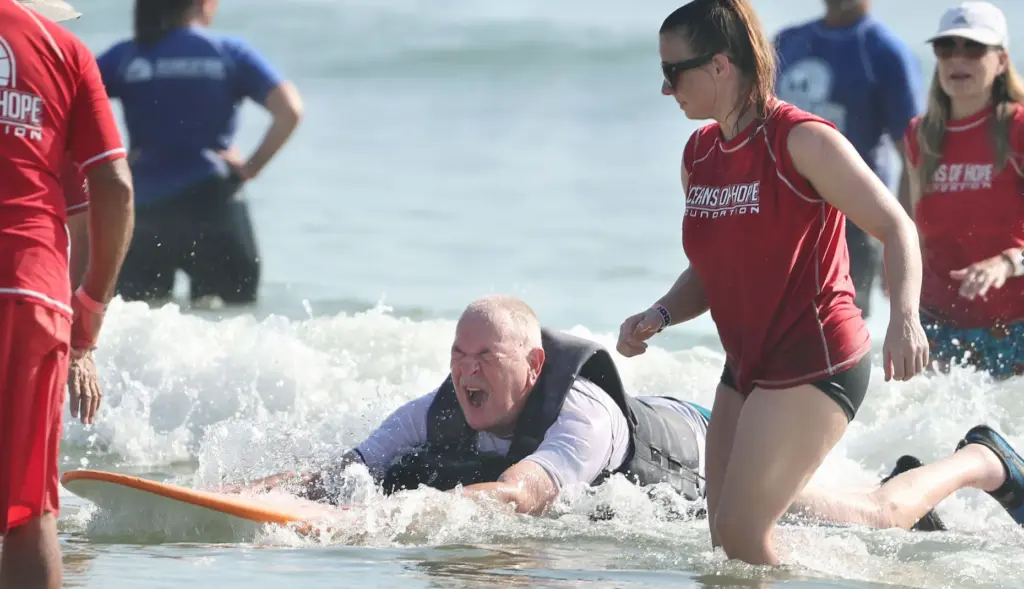 Navy veteran Rick Rettinger enjoys his ride on a surfboard...