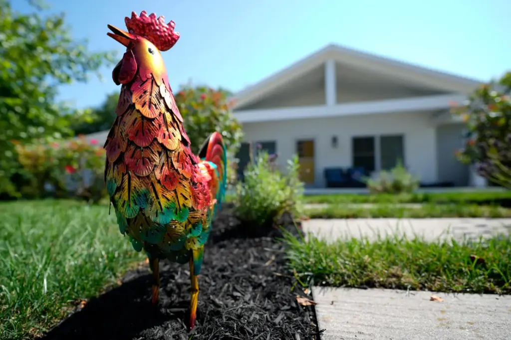 A small rooster stands outside a home as a sign...
