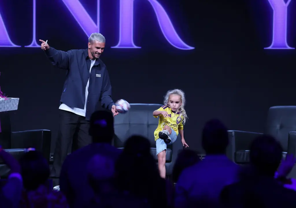 Antoine Griezmann watches a young girl kick an autographed soccer...