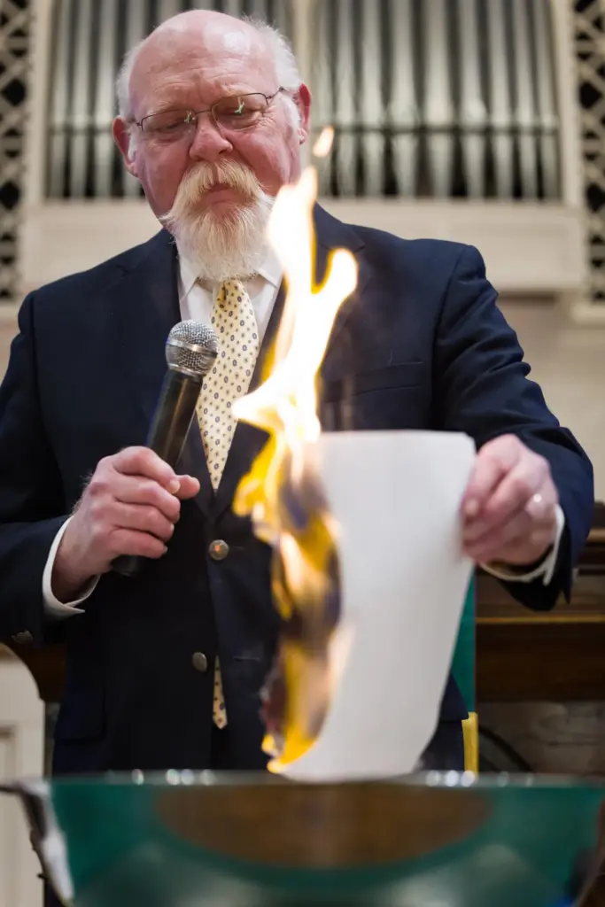 John Jackman, who leads Trinity Moravian Church, burns a list names of those with cleared debt.