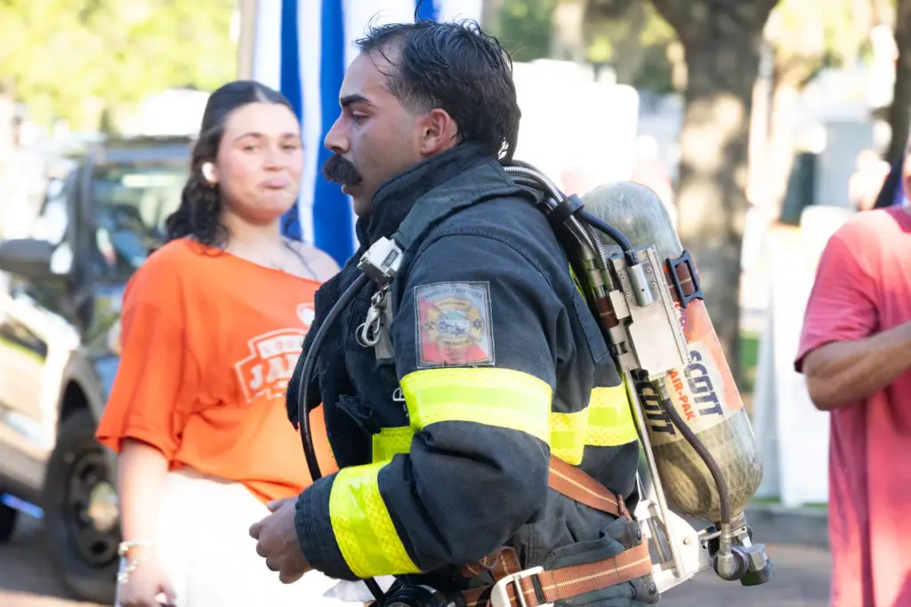 An Osceola Fireman running in uniform reaches the finish line...