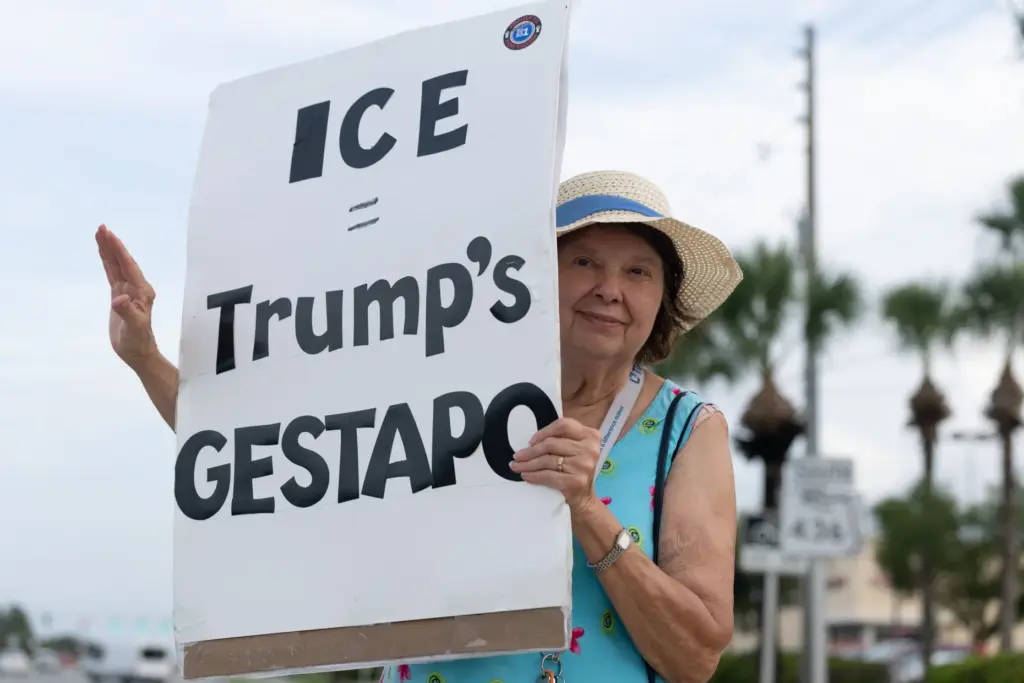 Protester holds a sign and waves to supporters during the...