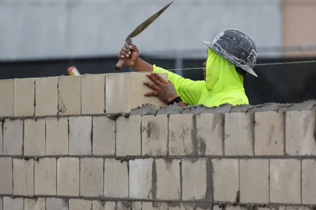 A mason from Sagewood Corp. builds the exterior walls of...