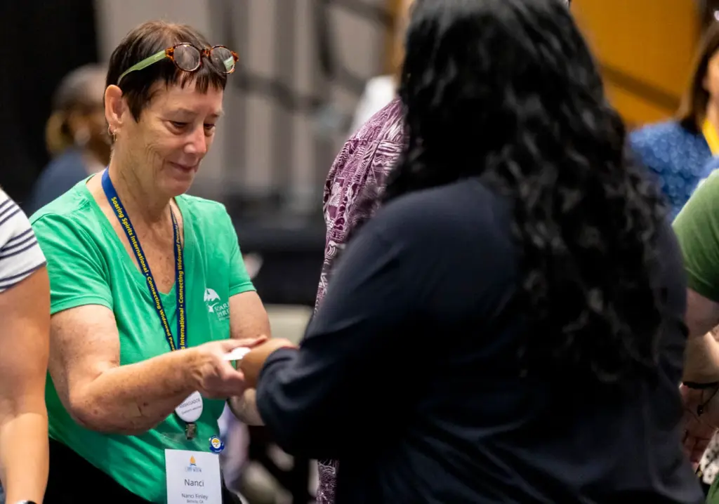 Nanci Finley of California passes a paper butterfly to other...