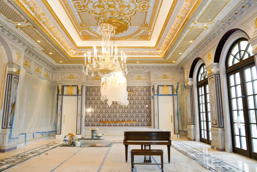 Gilded scrollwork, a grand piano and crystal chandeliers fill a...