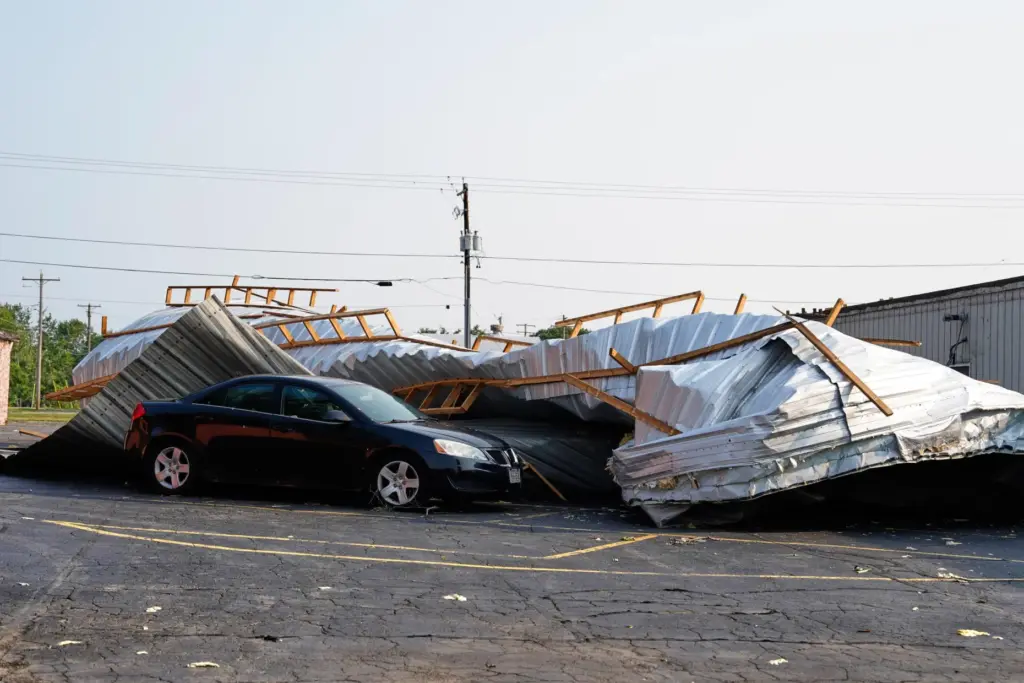 A car sits in a parking lot under a collapsed...