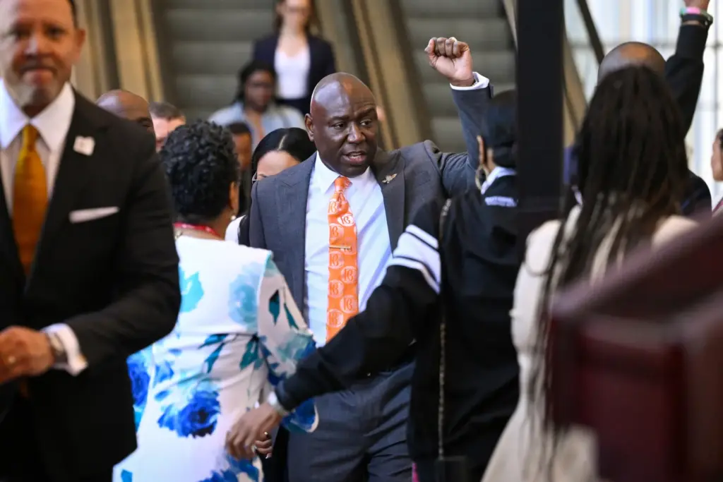 Attorney Ben Crump raises his fist as he arrives with...
