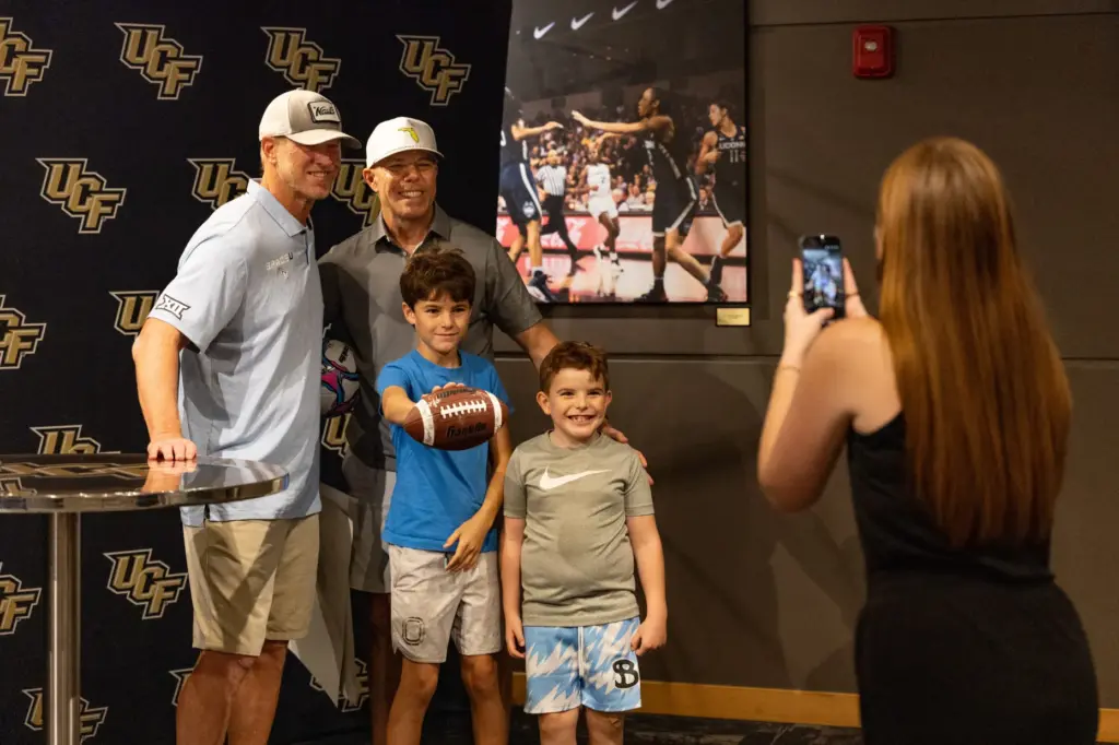 Knightâs Football Coach Scott Frost, left, takes a photo with...