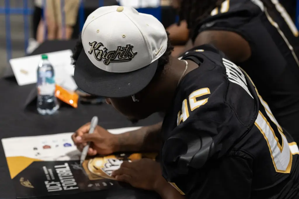 Knightâs Football Player Quentin Hatch signs an autograph for a...
