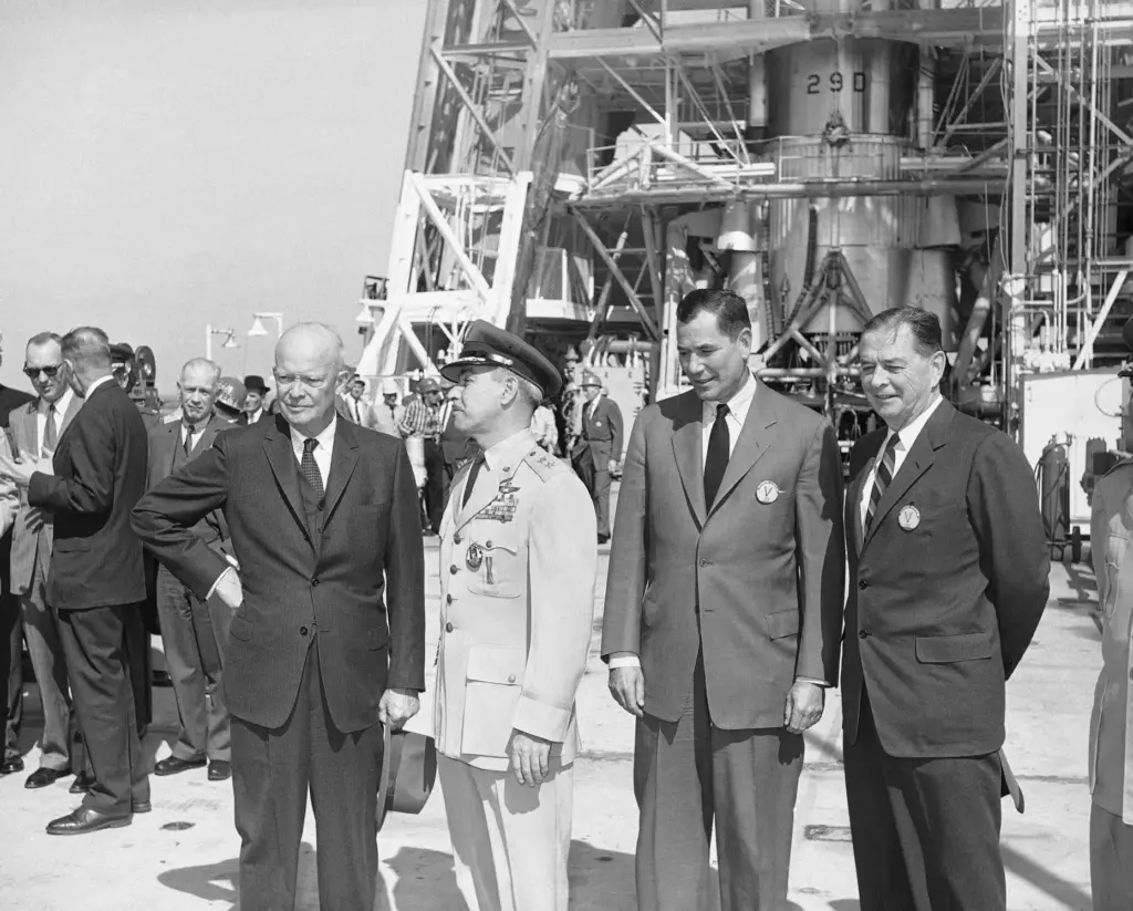 President Dwight Eisenhower is accompanied by two Defense Department chiefs...