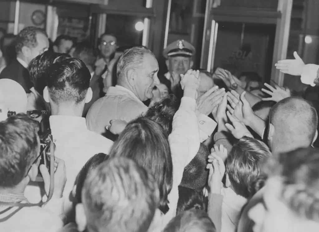 President Lyndon B. Johnson is engulfed by a hand-shaking crowd...