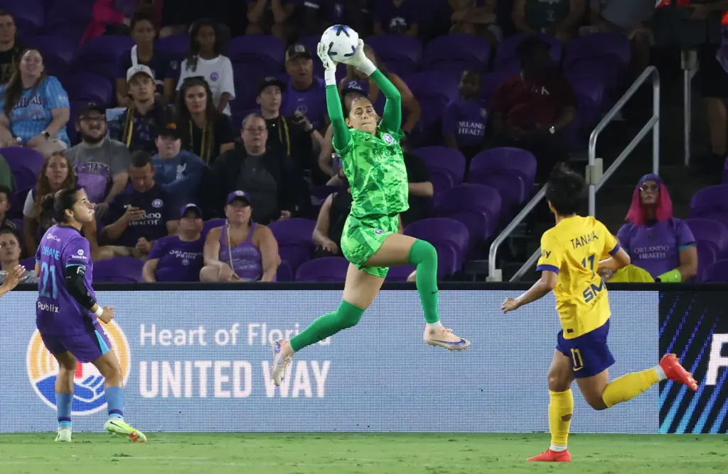 Orlando goalkeeper Cosette Morche leaps high to grab the ball...
