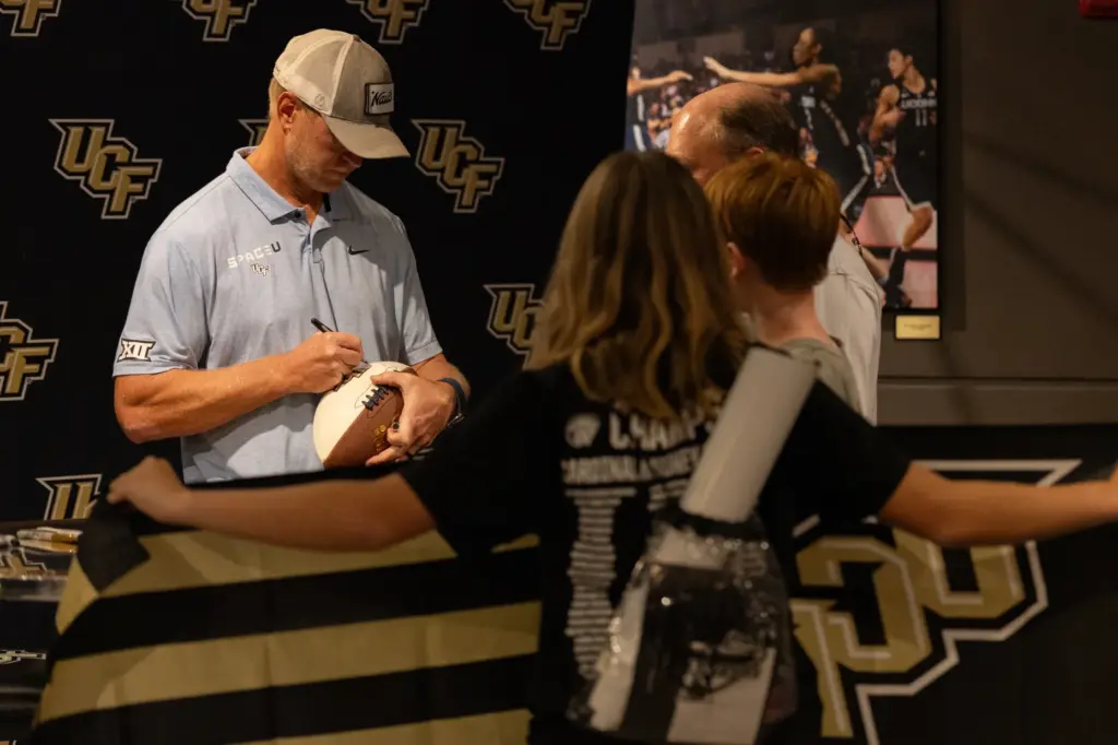 Knightâs Football Coach Scott Frost signs a fanâs football during...