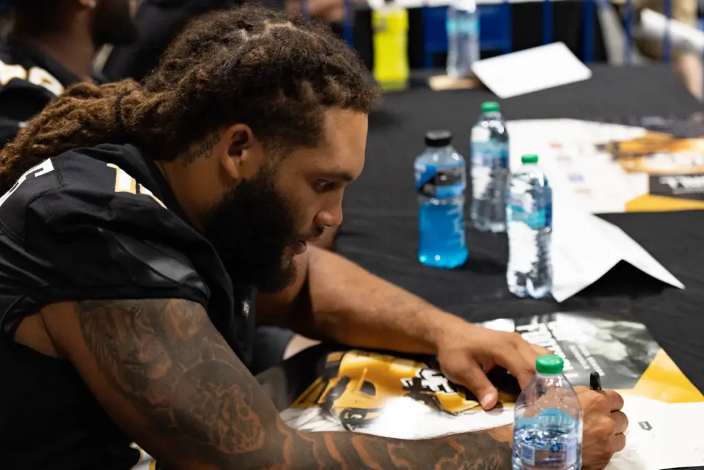 Knightâs Football Player Sincere Edwards signs an autograph for a...