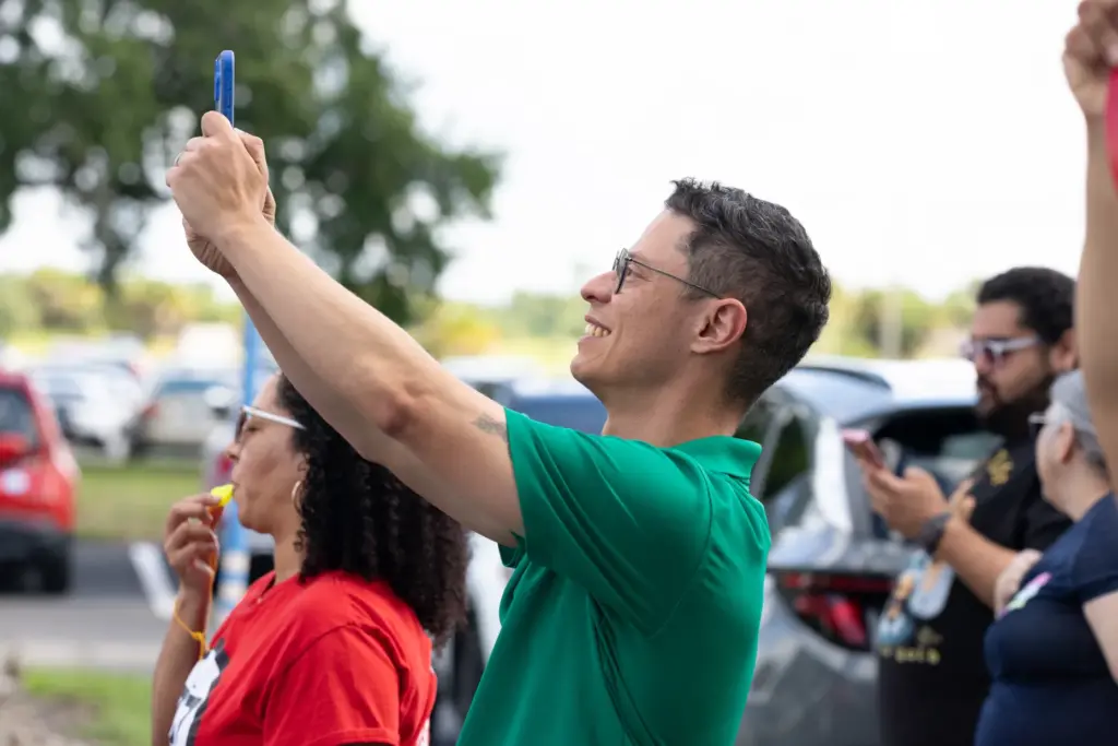 Candidate Felipe Sousa-Lazaballet takes a photo while marching with hundreds...
