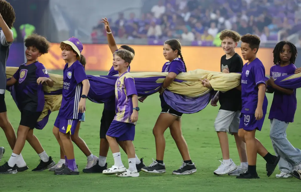 Kids enjoy carrying a banner on the pitch before the...