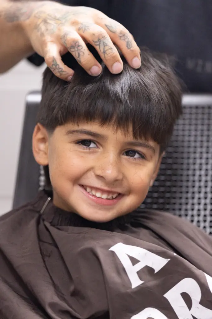 Altas Avila smiles while he gets his haircut by Barber...