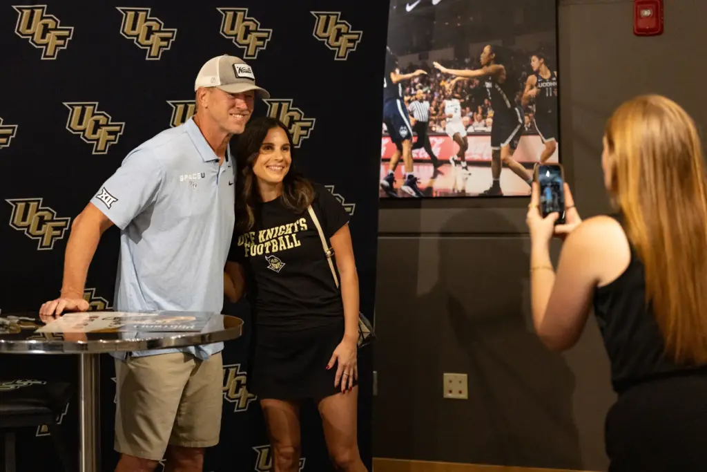 Knightâs Football Coach Scott Frost, left, takes a photo with...