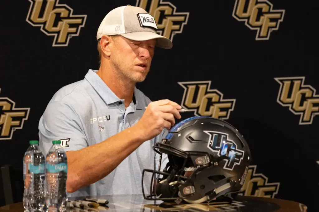 Knightâs Football Coach Scott Frost signs a fanâs helmet during...
