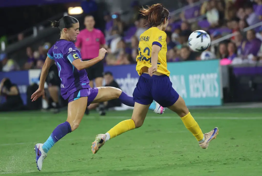 Orlando player Haley McCutcheon (left) kicks the ball away from...