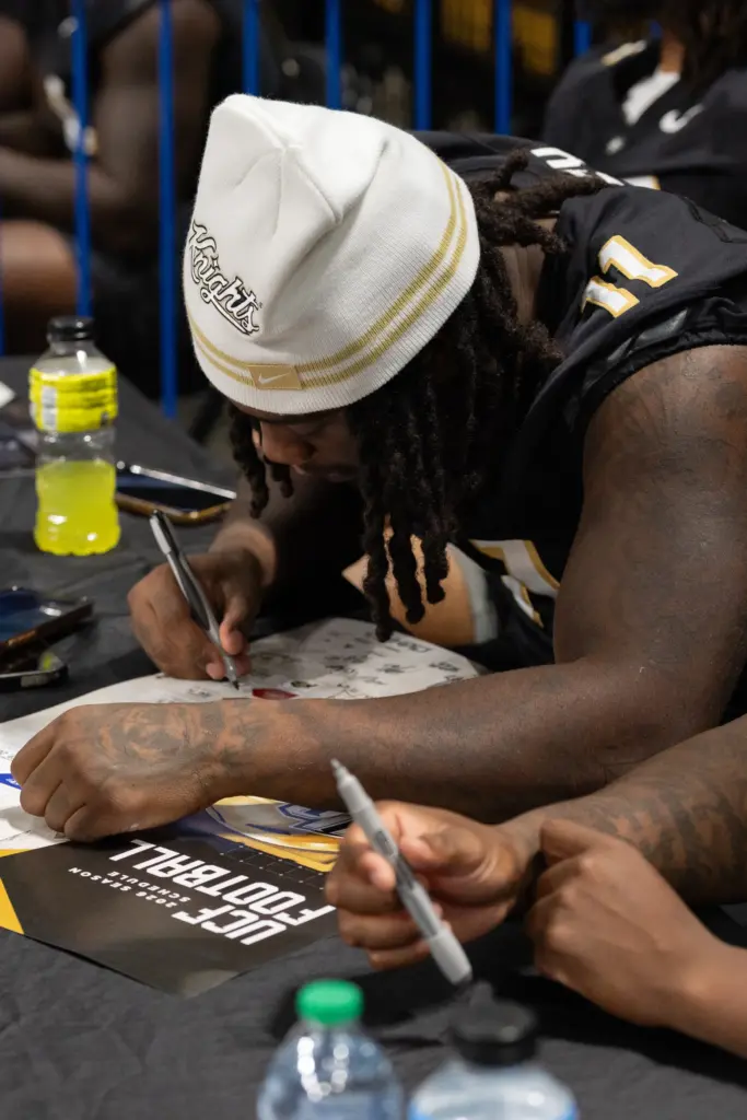 Knightâs Football Player Ken Talley signs an autograph for a...