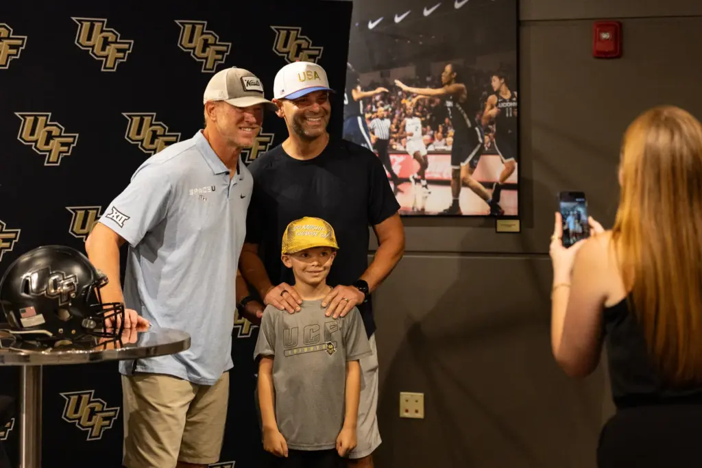 Knightâs Football Coach Scott Frost, left, takes a photo with...